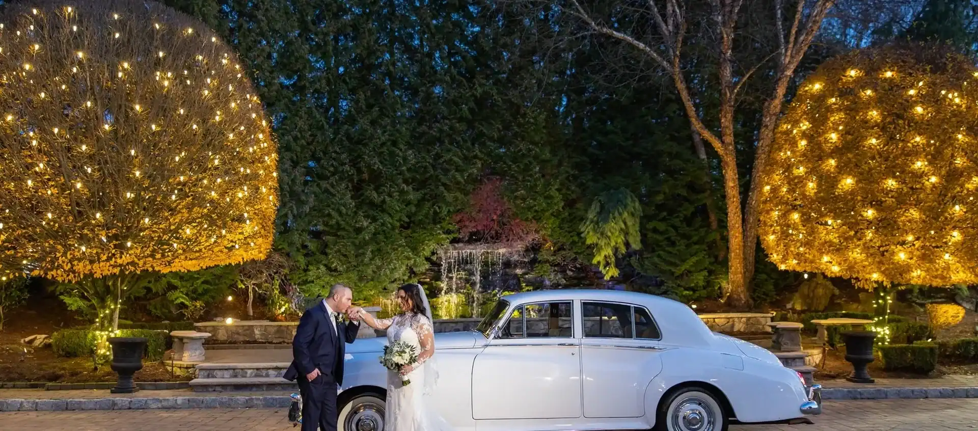 Bride and groom posing with Moonlight Limo white Rolls Royce on wedding day